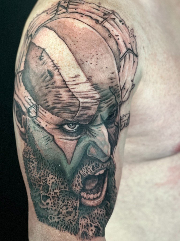 Illustrative realism Kratos portrait tattoo on an upper arm